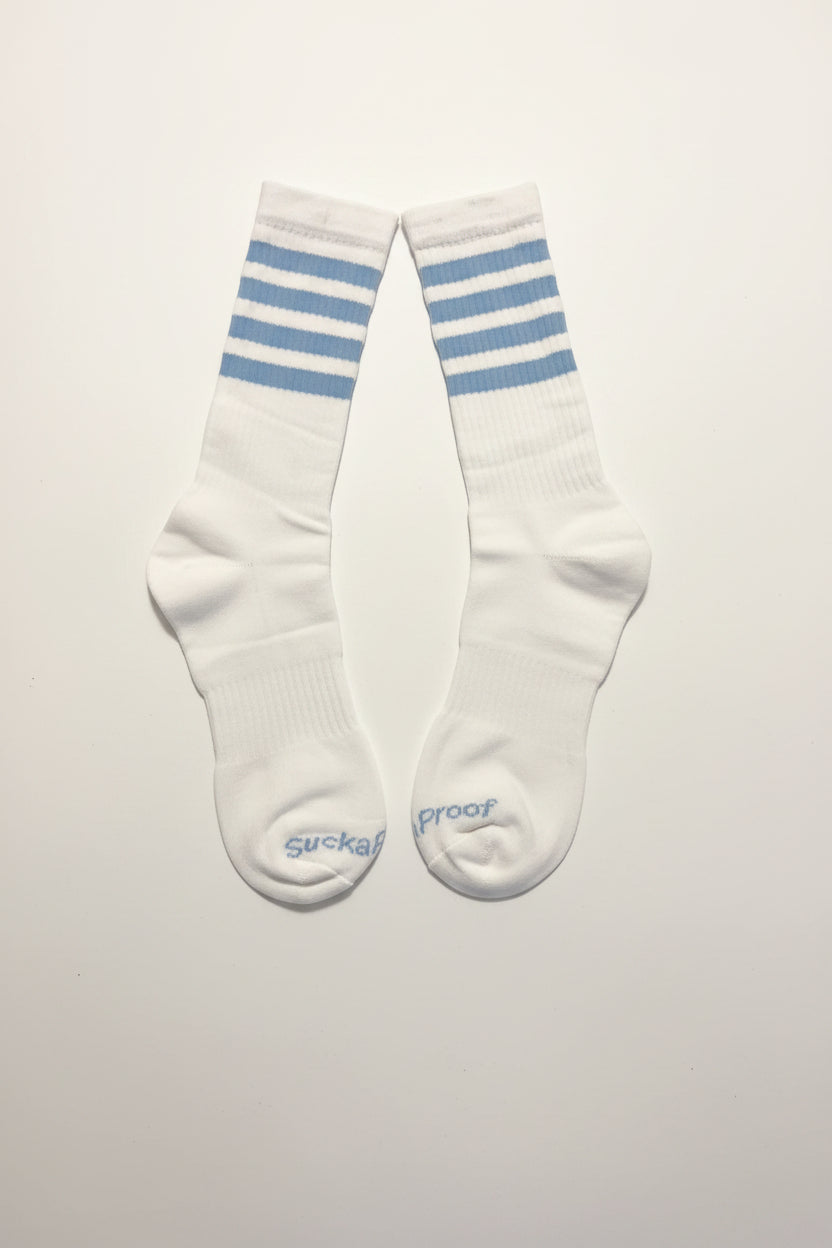 Sucka Proof white crew socks with sky blue athletic stripes and signature branding.
